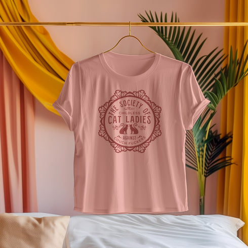 The Society of Childless Cat Ladies Against Couch Fuckers" 2024 election T Shrort design featuring two cats in an ornate circular frame, available in white and purple.